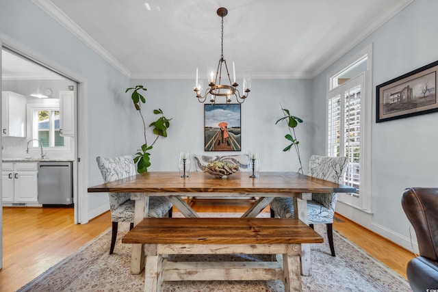 dining space with a chandelier, light wood finished floors, ornamental molding, and baseboards