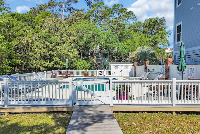 view of pool with fence, a patio, and view of wooded area