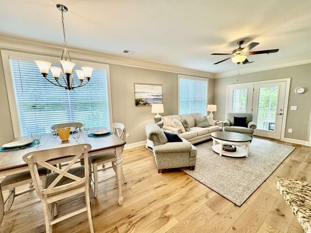 living room with a chandelier, light wood-style flooring, baseboards, a ceiling fan, and crown molding