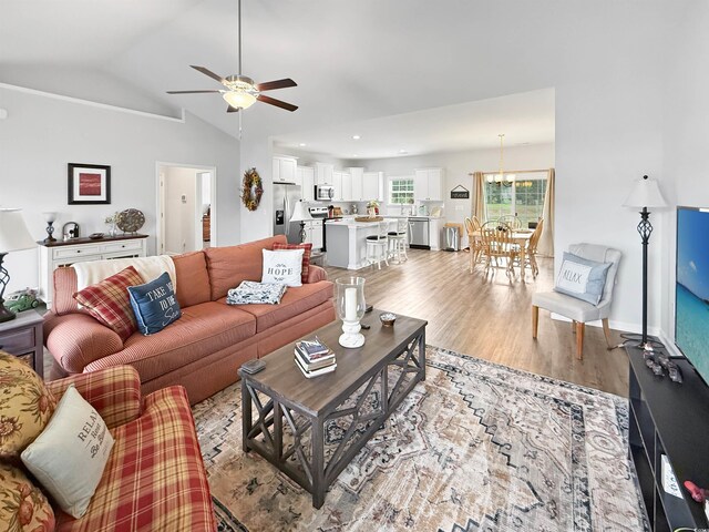 living room with light wood-style flooring, ceiling fan, lofted ceiling, and baseboards
