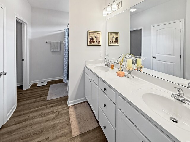 bathroom featuring wood finished floors, a shower, vanity, and baseboards