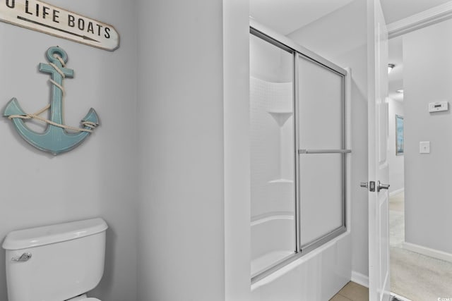 bathroom with toilet, shower / bath combination with glass door, and baseboards