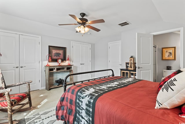 carpeted bedroom featuring multiple closets, lofted ceiling, and a ceiling fan