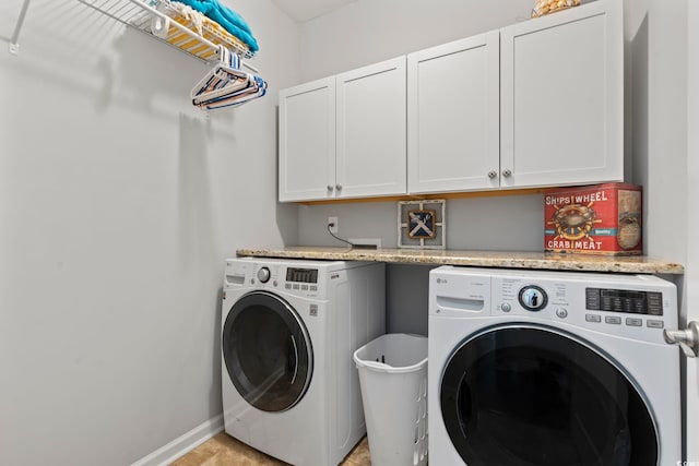 clothes washing area featuring cabinet space, washing machine and dryer, and baseboards