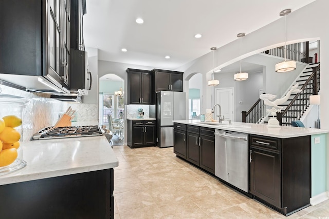 kitchen with appliances with stainless steel finishes, arched walkways, tasteful backsplash, a sink, and recessed lighting