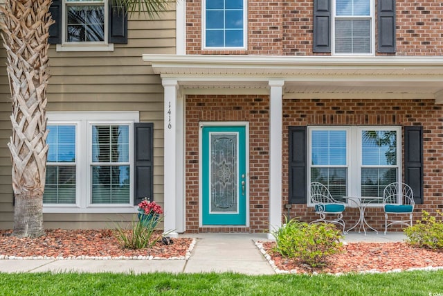 entrance to property with brick siding and covered porch