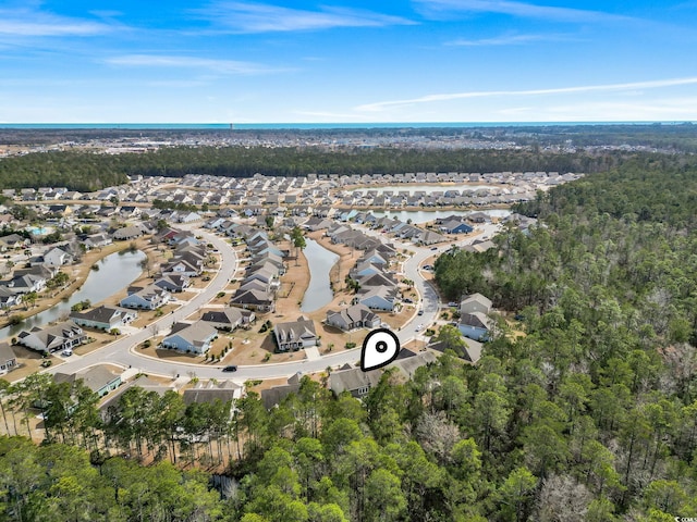 view of property location with nearby suburban area, a large body of water, and a forest