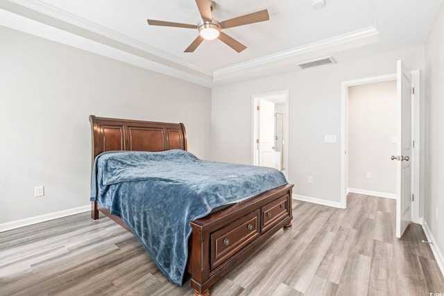 bedroom featuring a tray ceiling, light wood-style flooring, ornamental molding, and baseboards