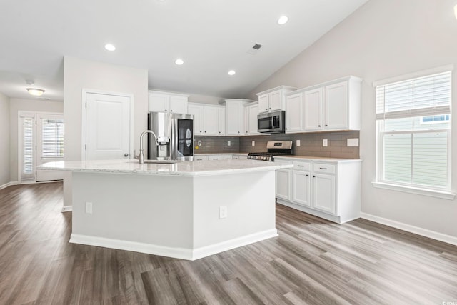 kitchen featuring stainless steel appliances, wood finished floors, white cabinets, backsplash, and a sink