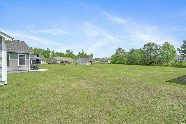 view of grassy yard with a residential view and a patio