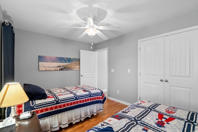 bedroom featuring wood finished floors, a closet, ceiling fan, and baseboards