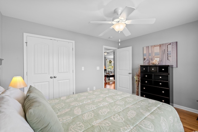 bedroom with a closet, wood finished floors, baseboards, and ceiling fan