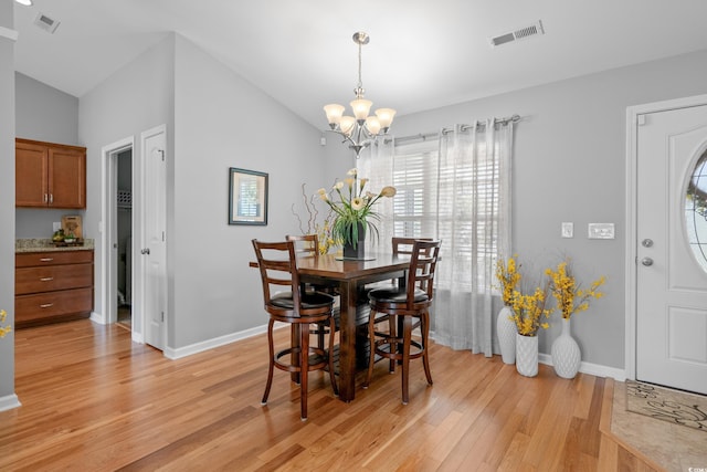 dining space featuring light wood-style flooring, lofted ceiling, a chandelier, baseboards, and plenty of natural light