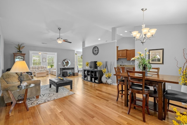 dining area with vaulted ceiling, a chandelier, a ceiling fan, light wood-style flooring, and recessed lighting