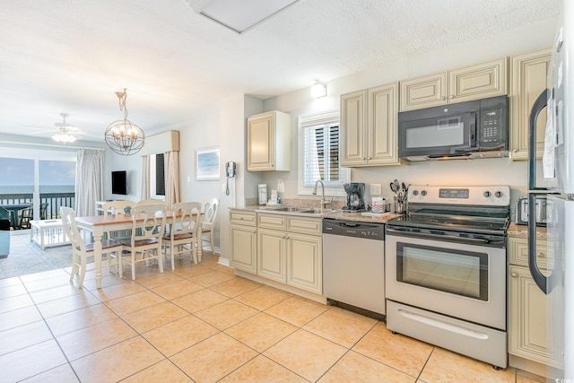 kitchen with cream cabinets, appliances with stainless steel finishes, light tile patterned floors, and a sink