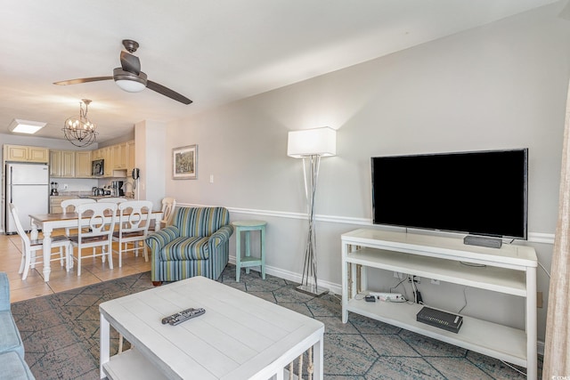 living room featuring a ceiling fan, a chandelier, light tile patterned flooring, and baseboards