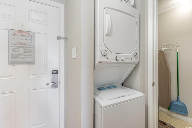 washroom with stacked washer / dryer and crown molding