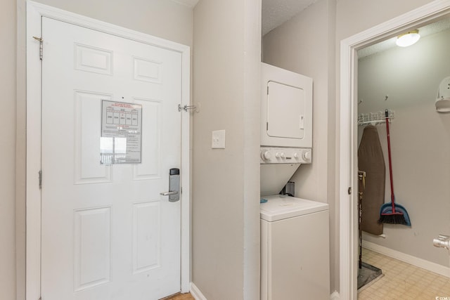washroom featuring stacked washing machine and dryer, light flooring, and baseboards