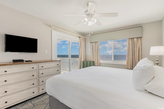 bedroom with access to exterior, a ceiling fan, and a water view