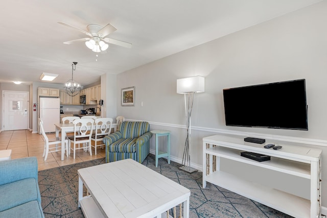 living area with a ceiling fan, a chandelier, light tile patterned floors, and baseboards