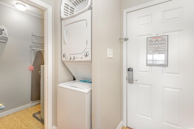 clothes washing area featuring stacked washing machine and dryer, baseboards, and tile patterned floors