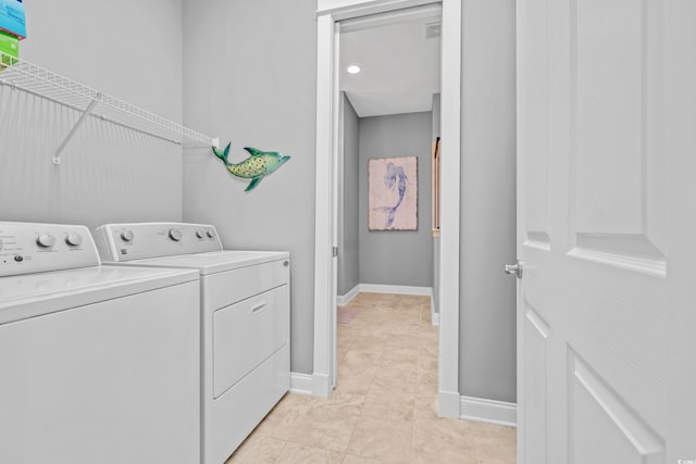 washroom with washing machine and dryer, baseboards, and light tile patterned floors