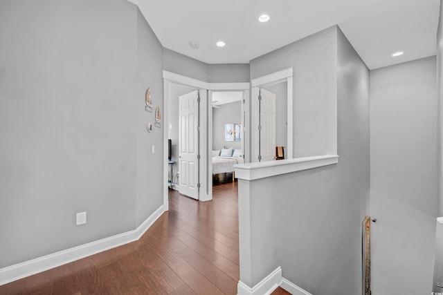 corridor featuring wood finished floors, baseboards, and recessed lighting