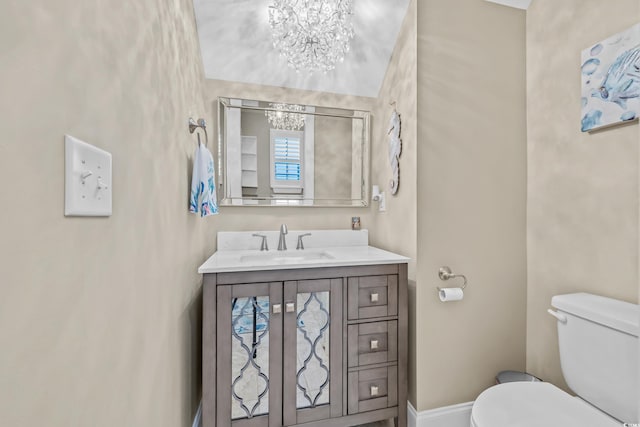 bathroom with a chandelier, toilet, vanity, and baseboards