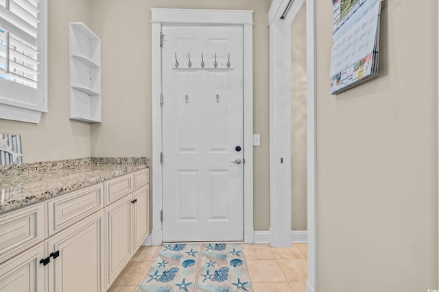 entryway with light tile patterned flooring and baseboards