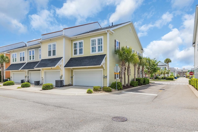 multi unit property featuring central AC unit, a garage, driveway, and a residential view