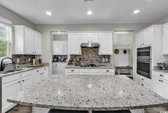 6239 Chadderton Cir, Myrtle Beach, SC 29579 - kitchen with stainless steel double oven, a sink, extractor fan, a center island, and white cabinets
