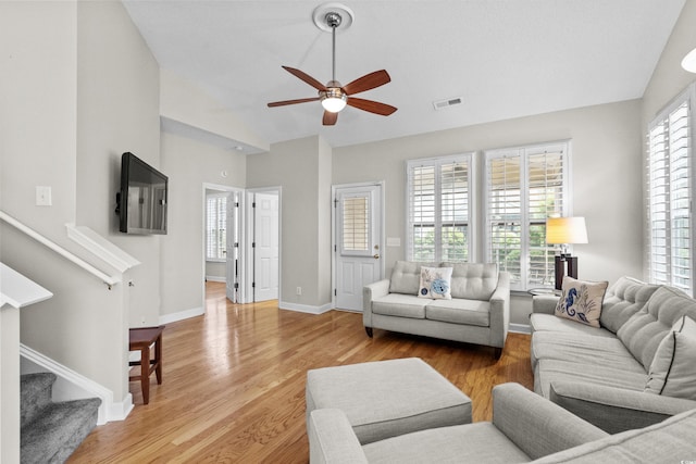 living room featuring ceiling fan, vaulted ceiling, stairway, light wood-style flooring, and baseboards