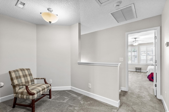 living area with carpet, baseboards, and a textured ceiling