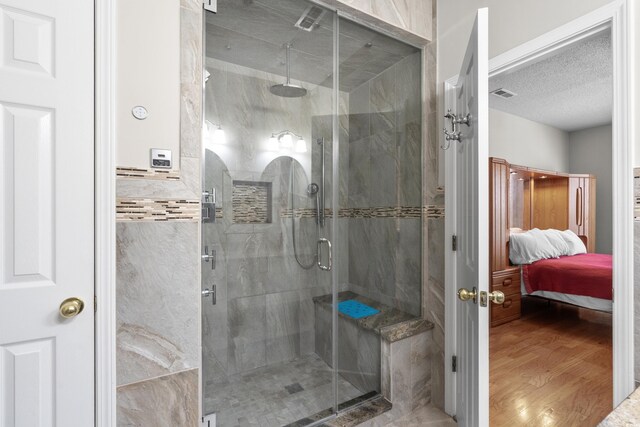 bathroom with wood finished floors, a stall shower, ensuite bathroom, and a textured ceiling