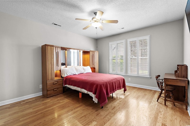 bedroom featuring light wood-style floors, a textured ceiling, baseboards, and a ceiling fan