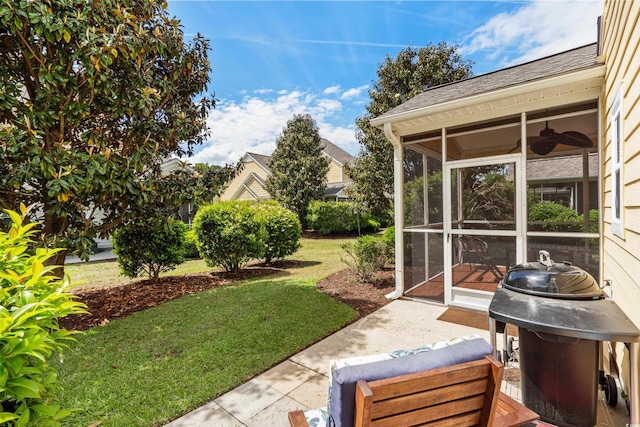 view of green lawn featuring a sunroom and a ceiling fan