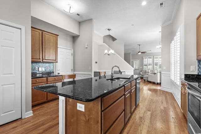 kitchen with a sink, light wood finished floors, ceiling fan, brown cabinets, and open floor plan