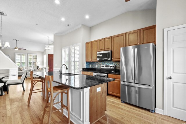kitchen featuring appliances with stainless steel finishes, ceiling fan, light wood finished floors, a sink, and open floor plan