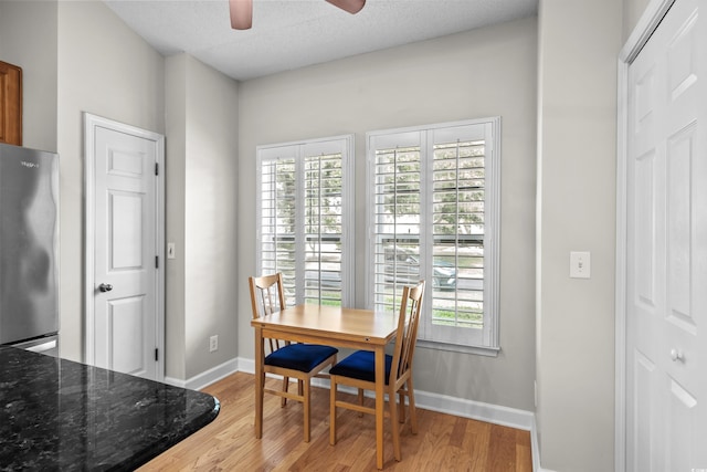 dining space featuring ceiling fan, light wood-style flooring, plenty of natural light, baseboards, and a textured ceiling