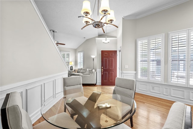 dining space with a chandelier, a decorative wall, wainscoting, a ceiling fan, and light wood-type flooring