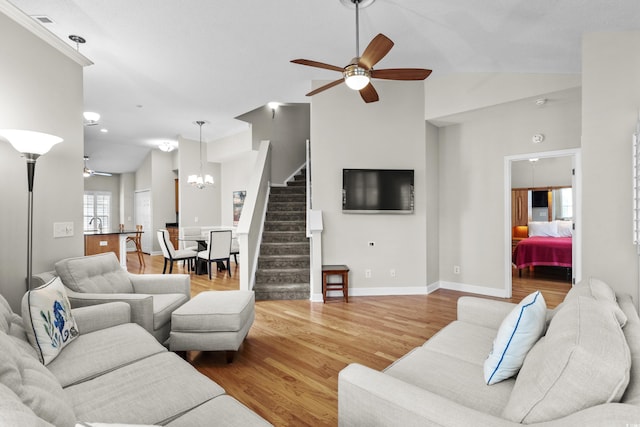 living room with ceiling fan, vaulted ceiling, stairway, wood finished floors, and baseboards