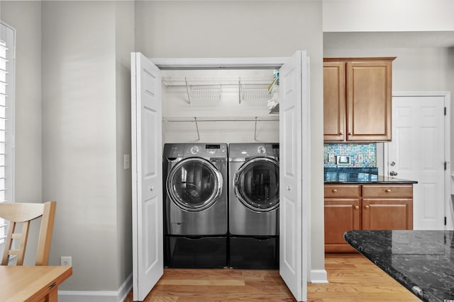 laundry room with separate washer and dryer, light wood-style flooring, and baseboards