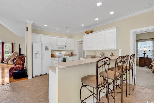 1729 Longleaf Dr, Myrtle Beach, SC 29575 - kitchen featuring white appliances, a peninsula, white cabinetry, crown molding, and a breakfast bar