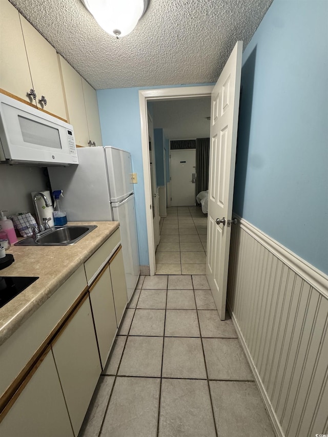 7500 N Ocean Blvd Unit 6120, Myrtle Beach, SC 29572 - kitchen featuring white microwave, a sink, light tile patterned flooring, light countertops, and a textured ceiling