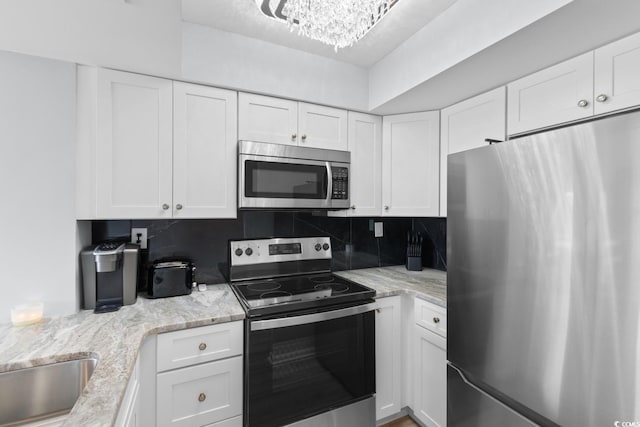 kitchen with appliances with stainless steel finishes, white cabinetry, and backsplash