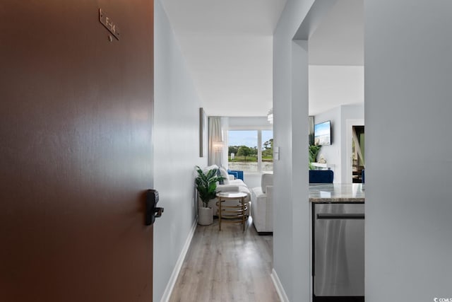 corridor with light wood-style flooring and baseboards
