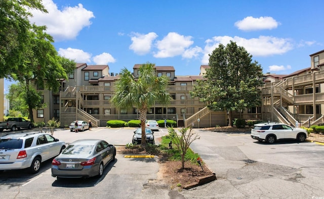 view of property with stairs and uncovered parking