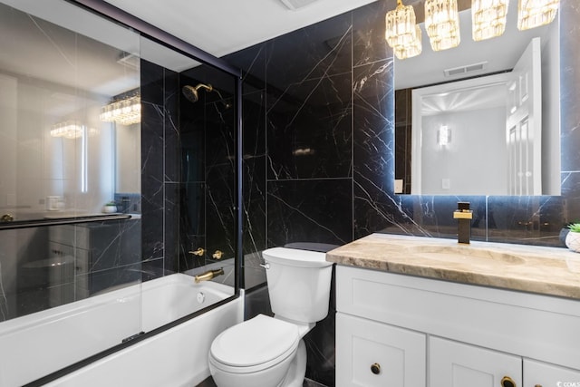 full bathroom with tile walls, enclosed tub / shower combo, toilet, and vanity