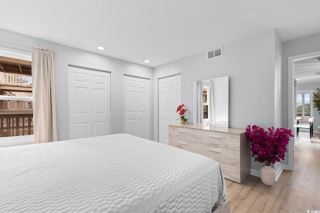 bedroom featuring light wood-style floors, recessed lighting, multiple closets, and baseboards