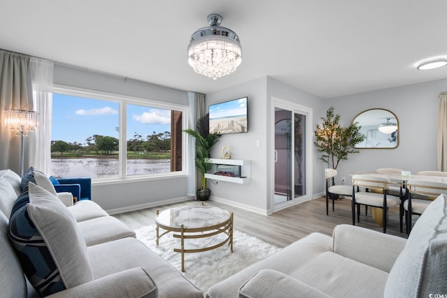living room featuring a chandelier, baseboards, and light wood-style floors